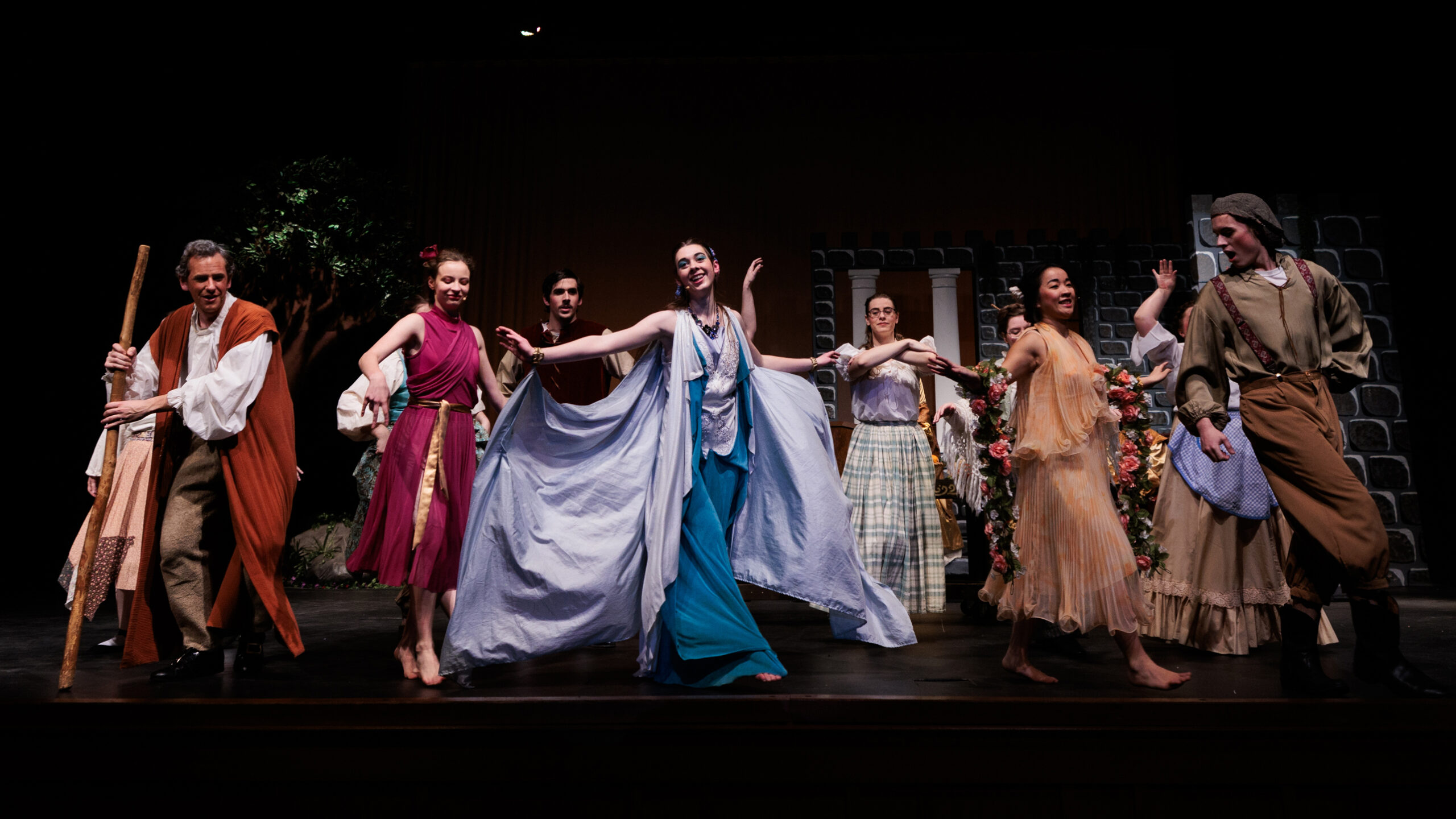 Cast members in vibrant costumes portraying characters from Sleeping Beauty, Briar Rose on stage, showcasing a lively performance.