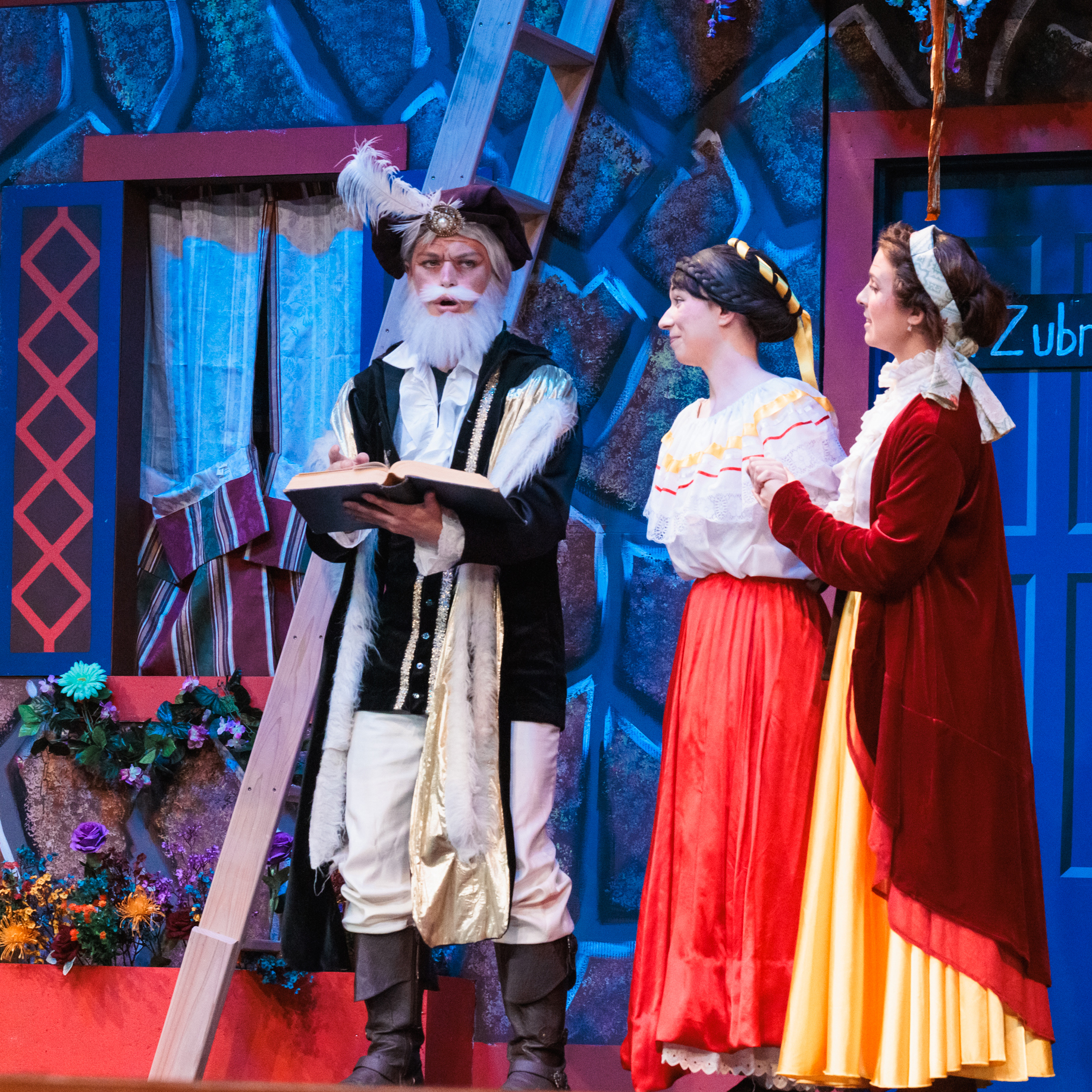 Three costumed actors perform on stage, bringing to life scenes from the comedic play "Fools."