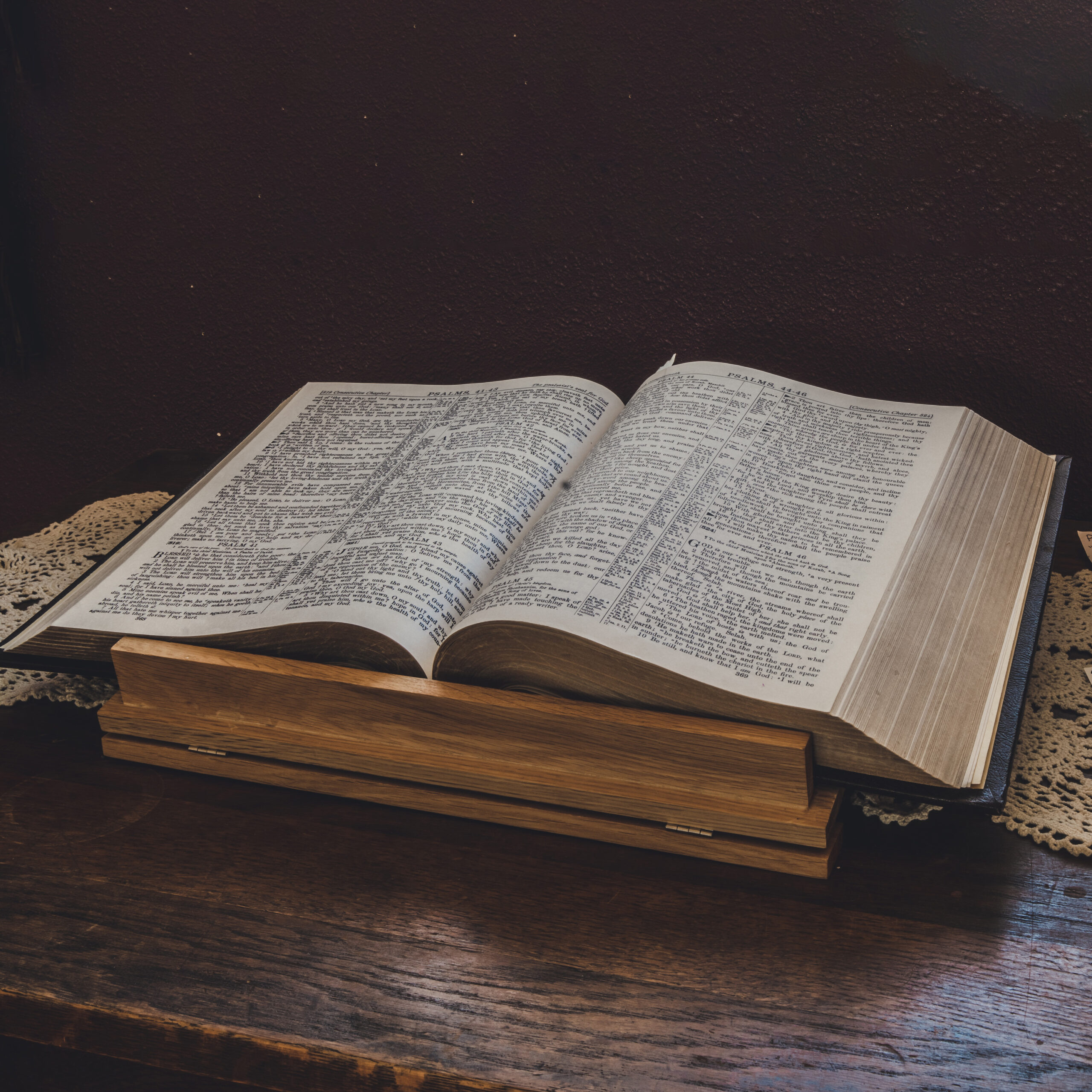 A wooden table supports an open Bible, inviting contemplation with its visible pages and text.