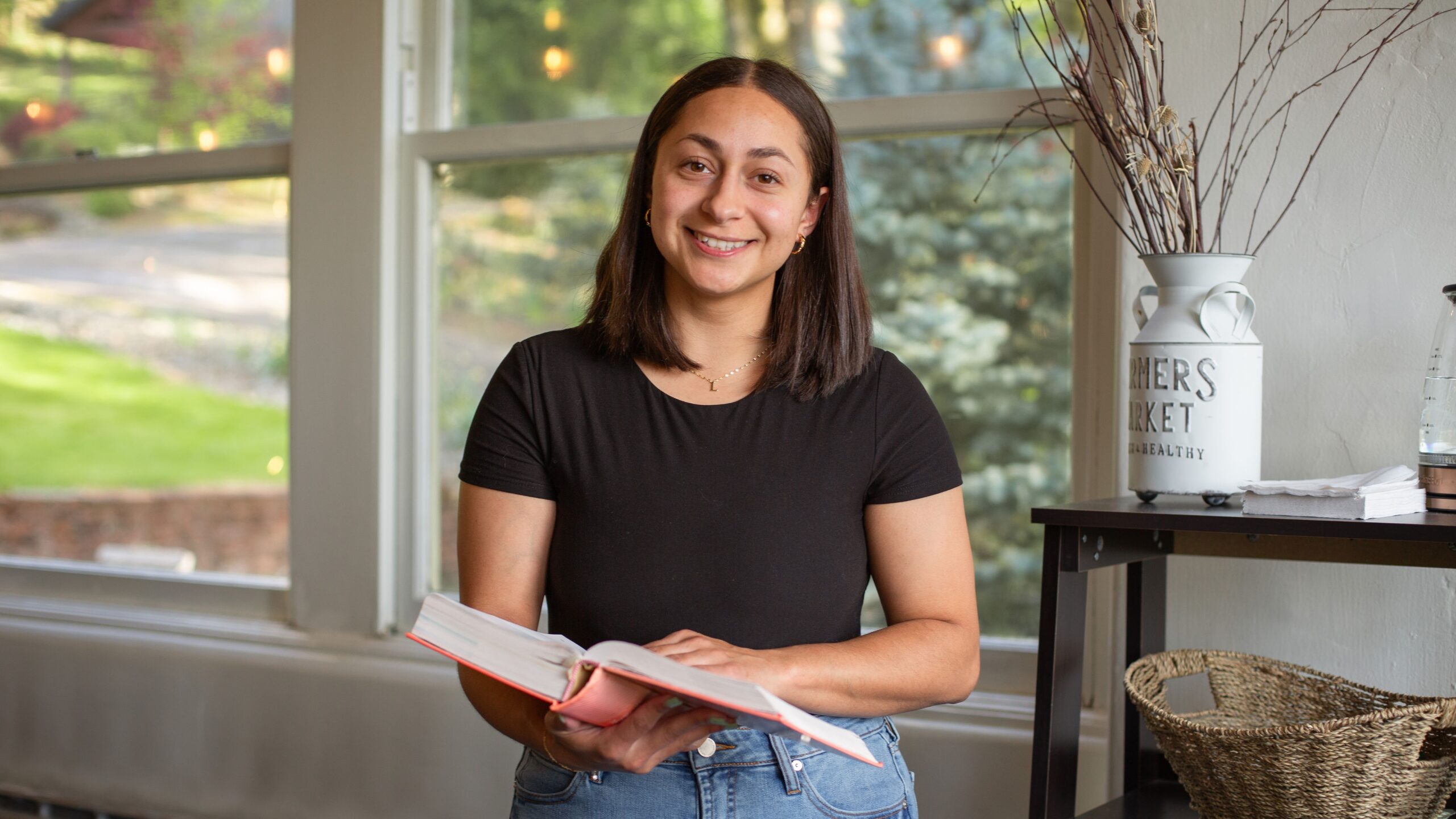 A woman smiles while holding a book in her hands, exuding joy and enthusiasm for reading.