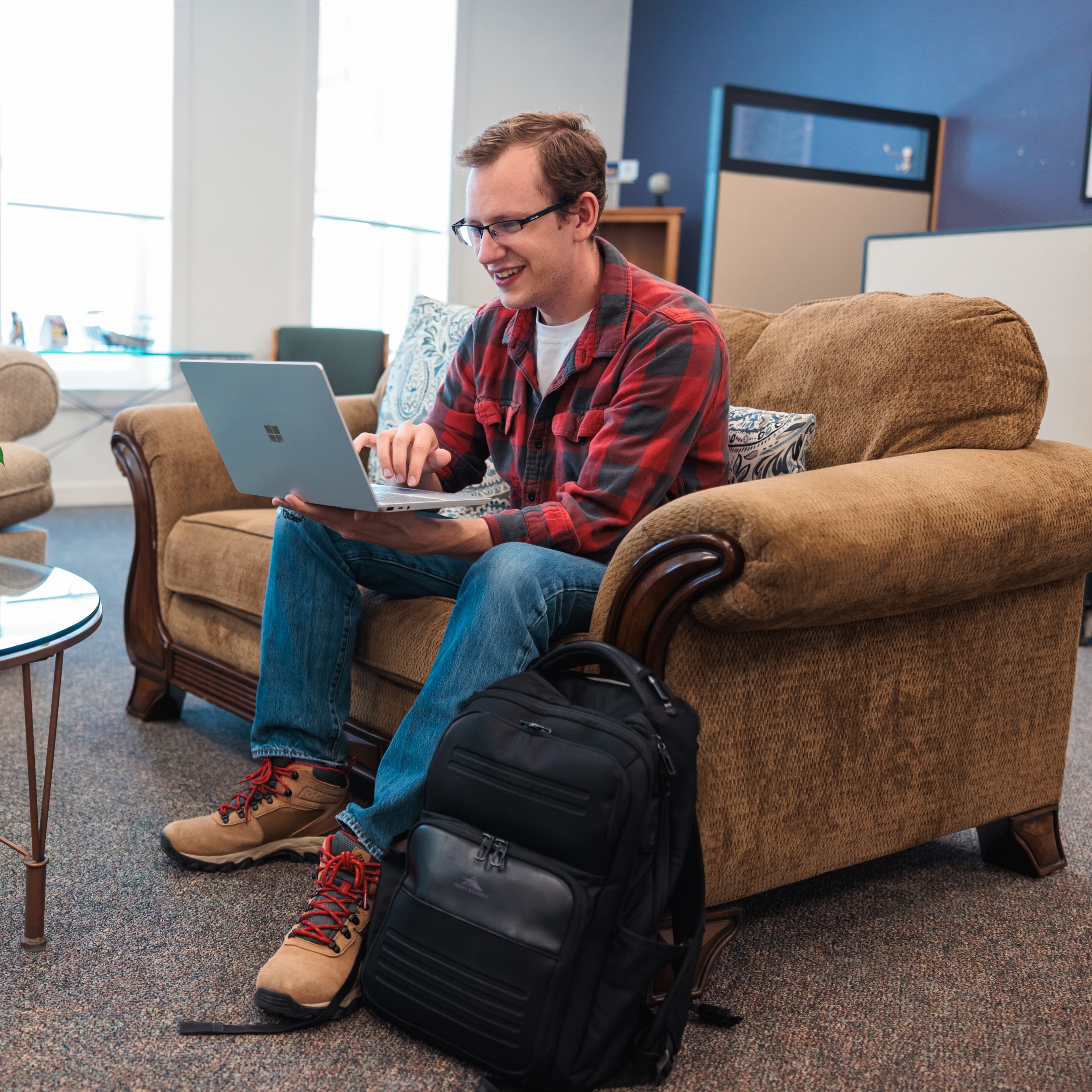 A man seated on a couch, studying in a cozy student study space.