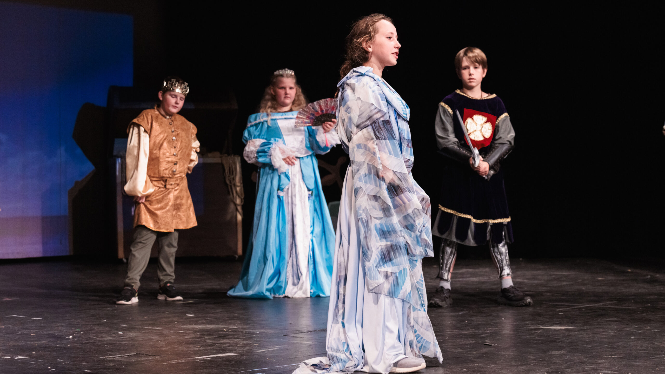 four young actors dressed as royalty perform on stage during Theatre Camp