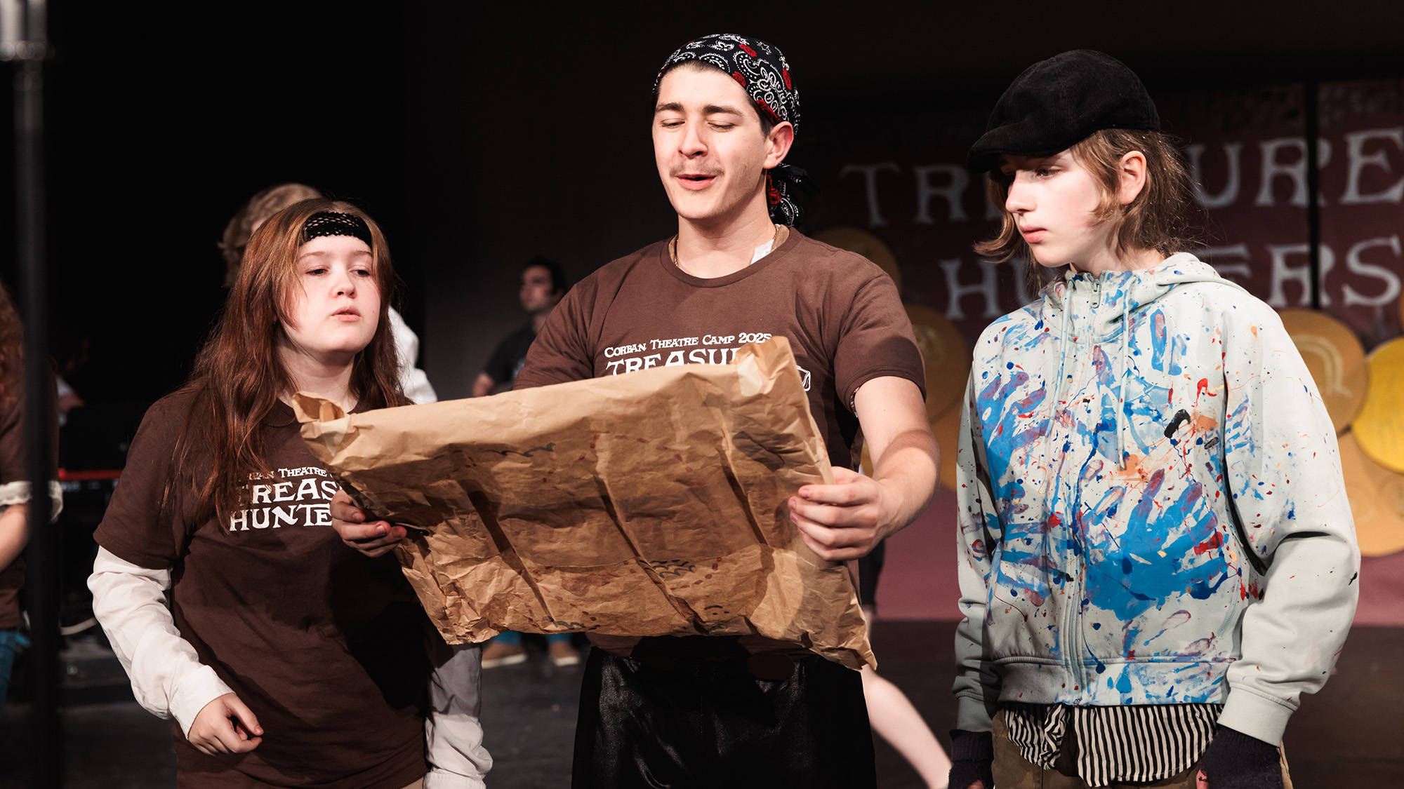 a group of young actors study a large map on stage during Theatre Camp