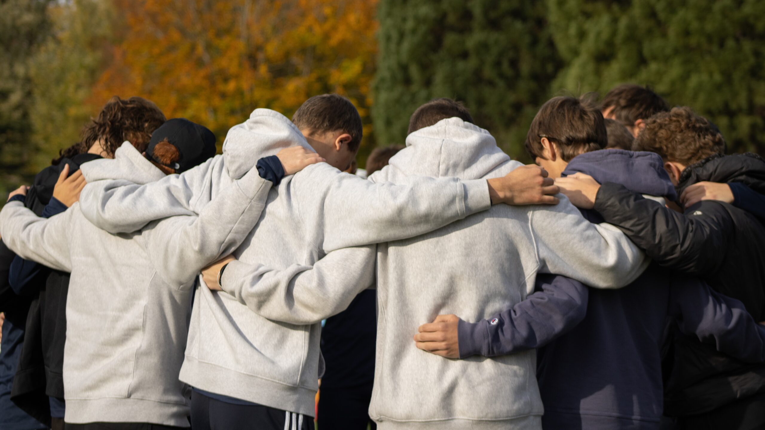 Young men gathered in a circle, celebrating after their cross country race.