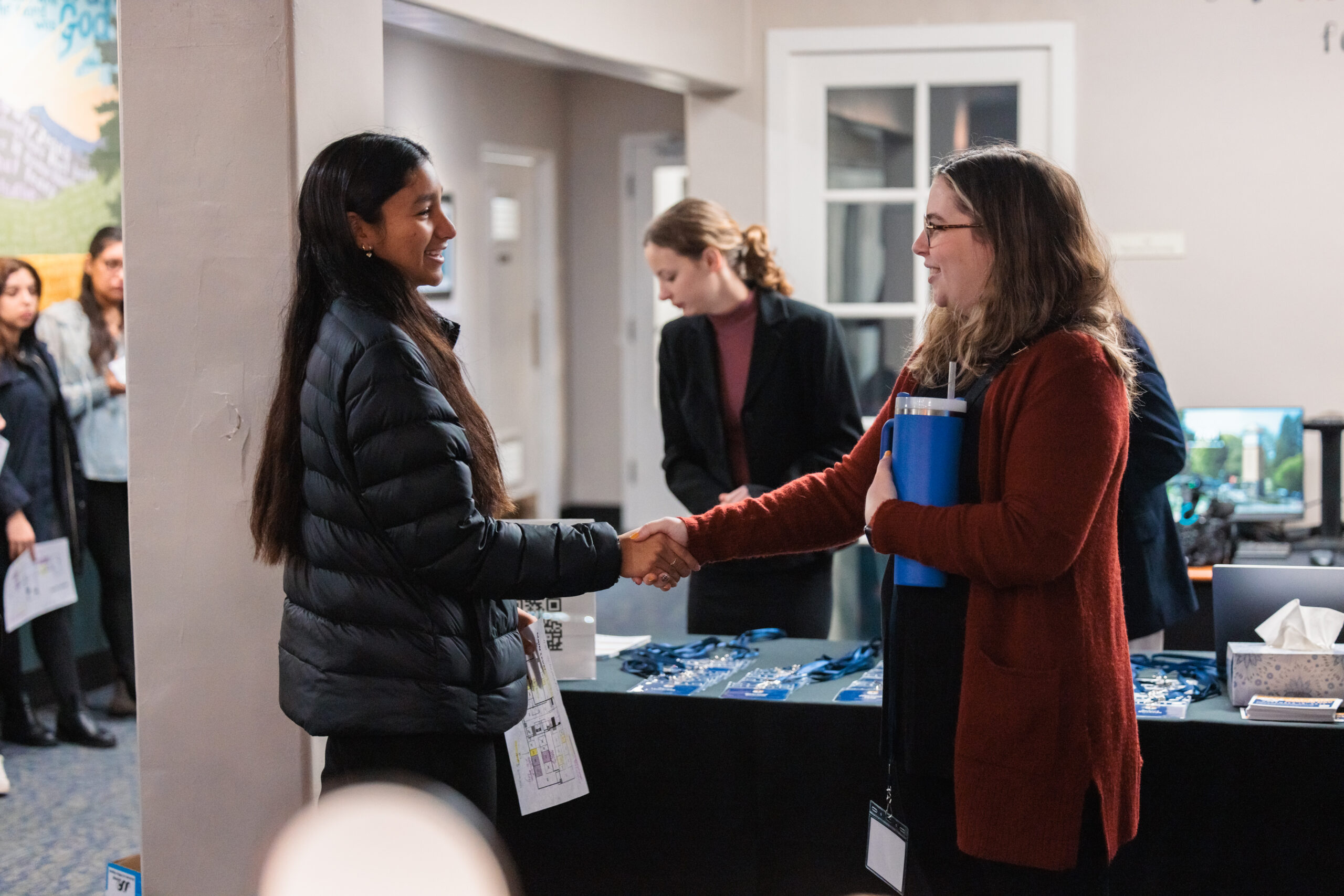 Two women shaking hands at Corban's mock interviews on Career Day, symbolizing a professional connection and networking opportunity.