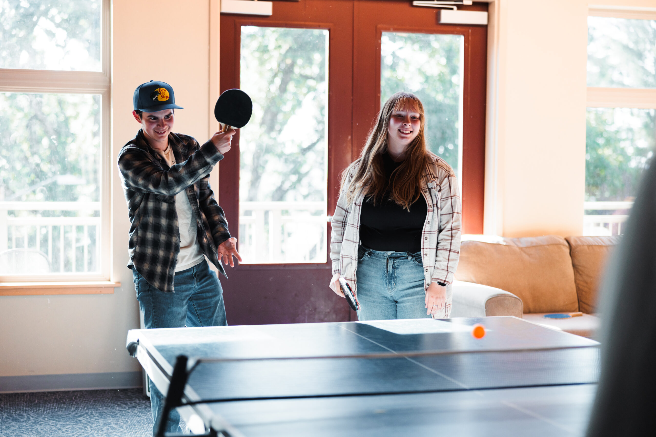 A man and a woman engaged in a lively game of ping pong, focused on the ball.