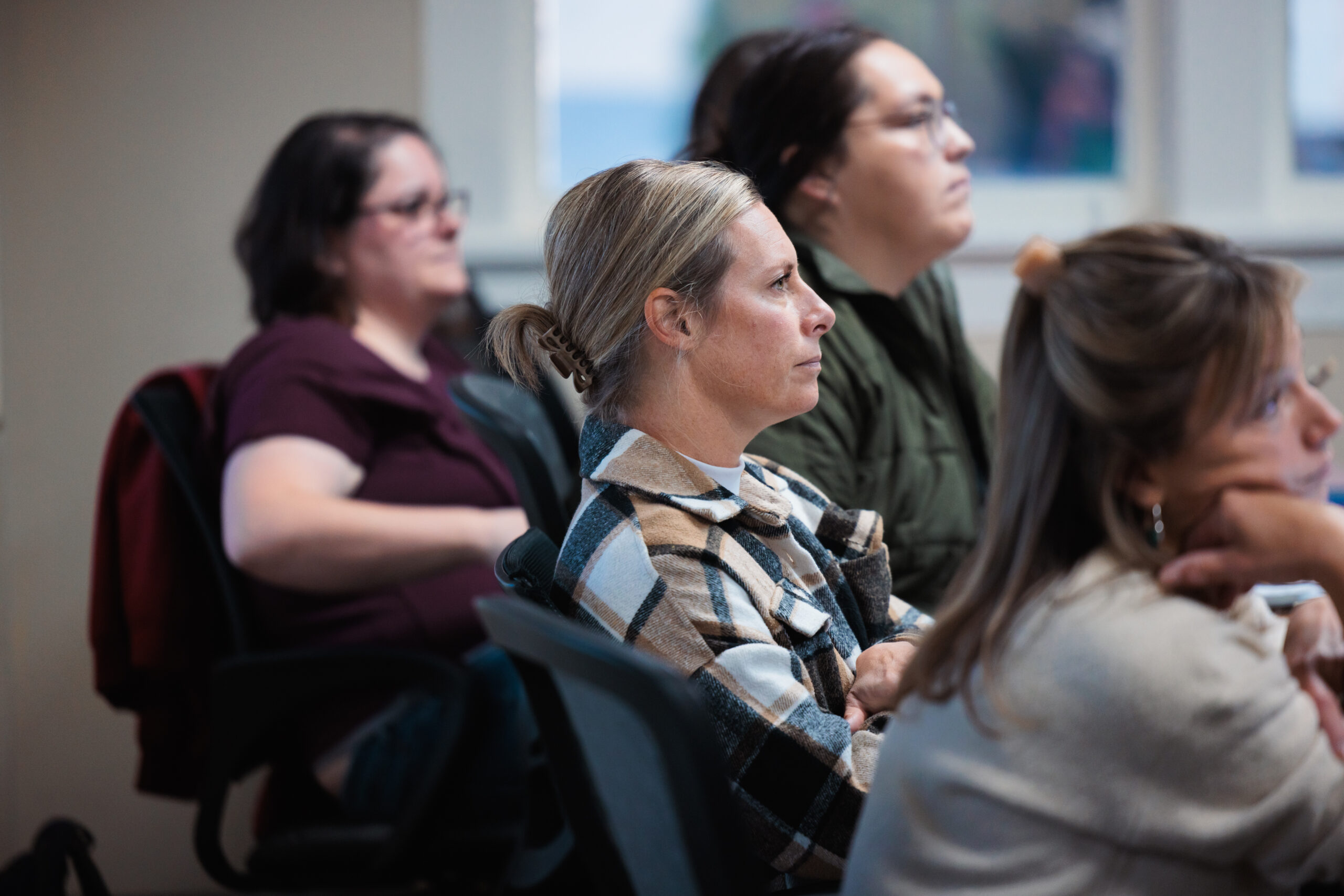 A group of women seated in a classroom, engaged in discussion and learning together.