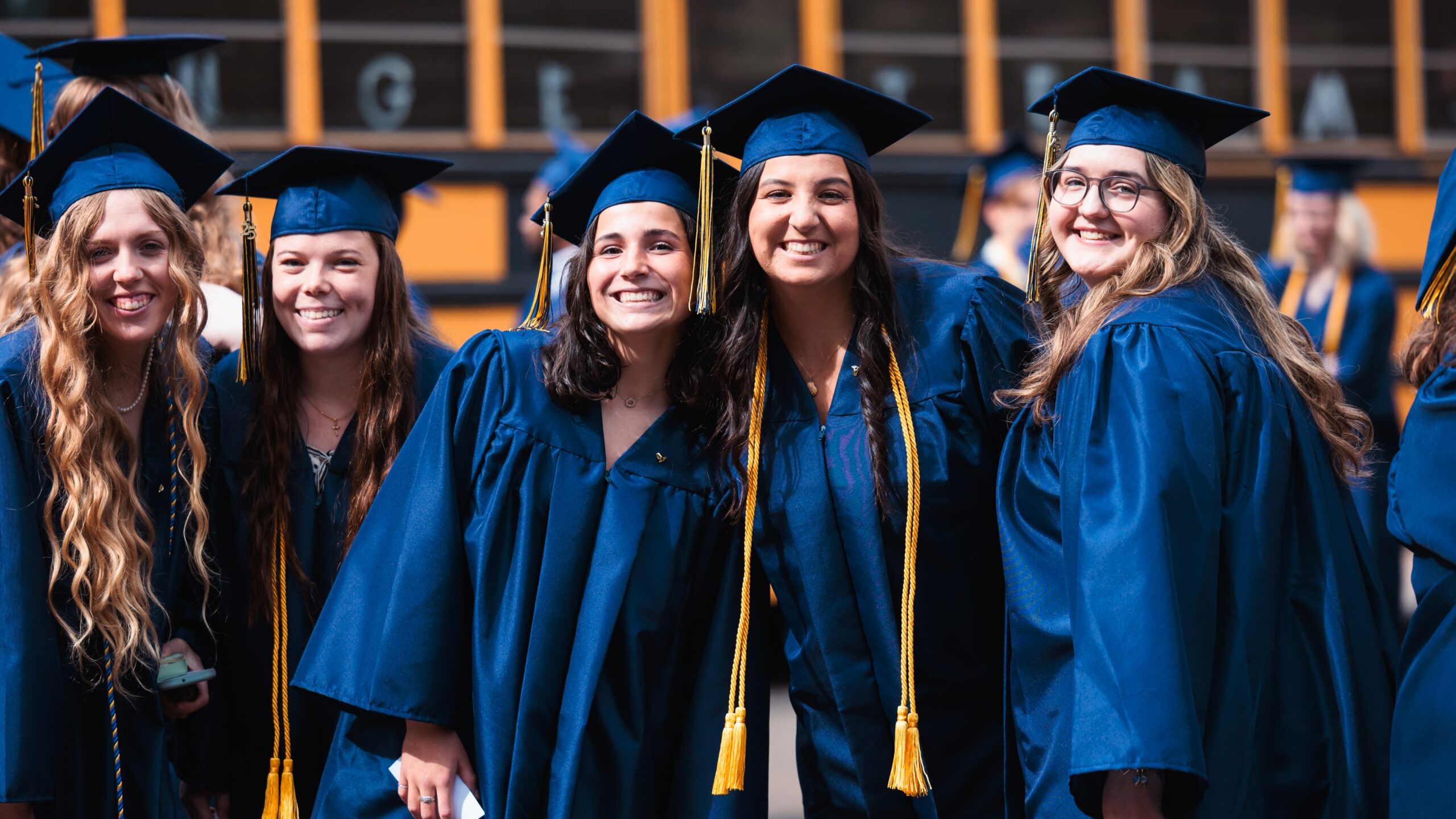 A group of graduates in caps and gowns pose for a photo outside before their commencement ceremony.