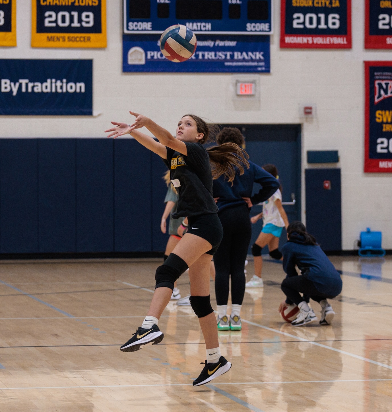 A girl jumps high to hit a volleyball, demonstrating her skill and enthusiasm for the sport.