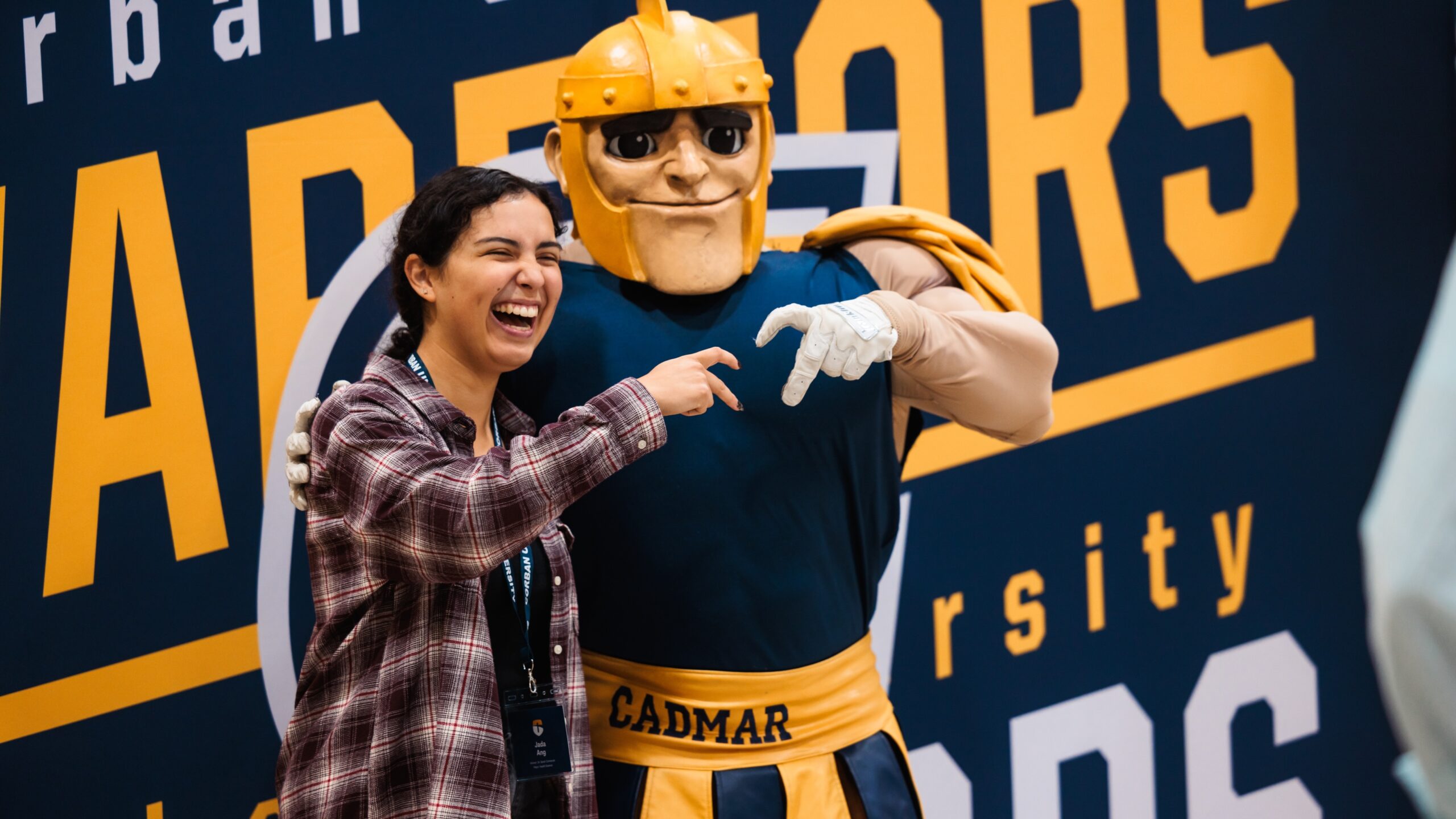 A woman poses beside Corban's mascot, Cadmar, at Warrior Welcome.