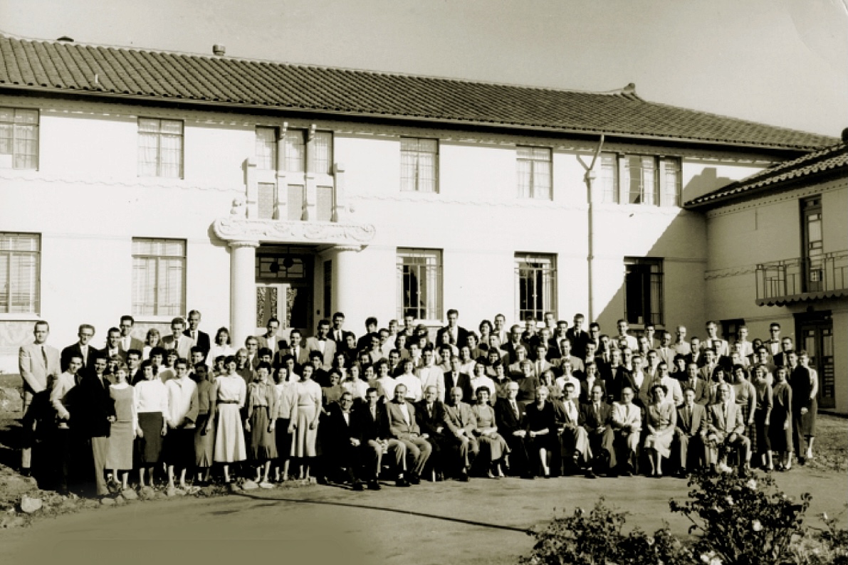 A group of people stand in front of the El Cerrito campus building, smiling.