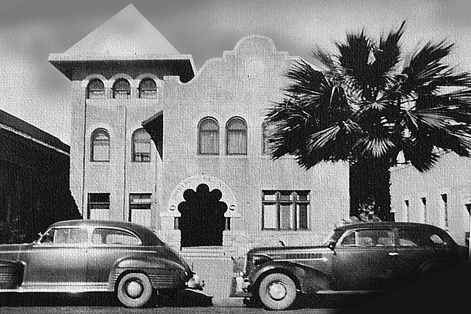 Black and white photo of two vintage cars parked in front of Phoenix Bible Institute.