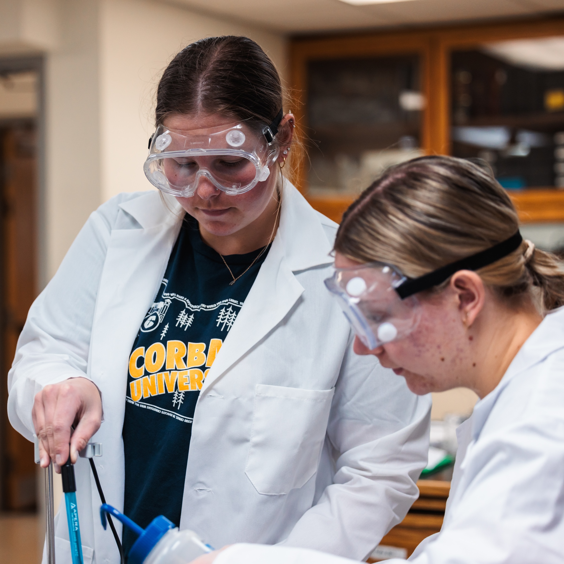 Two women wearing lab coats working collaboratively on a research project in a laboratory.