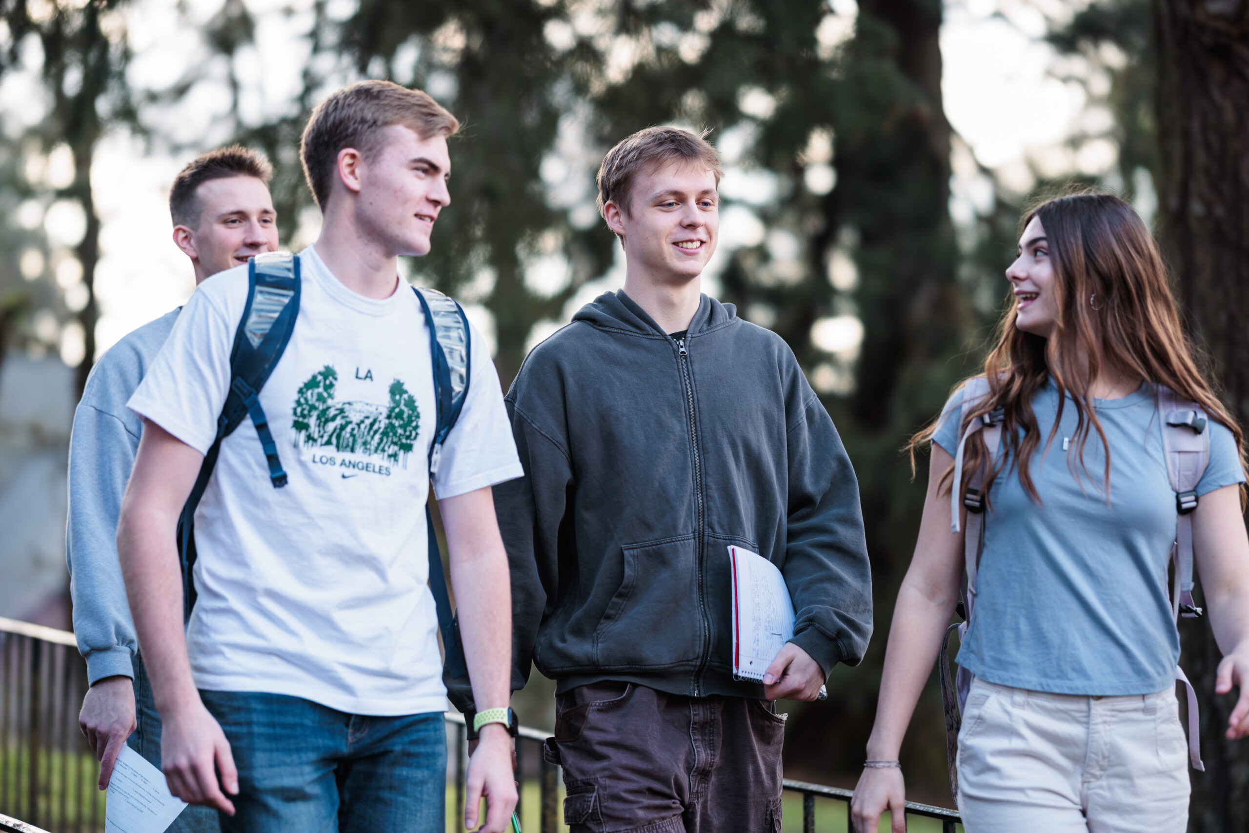 A group of four students walking on a path, engaged in conversation and enjoying the outdoors.