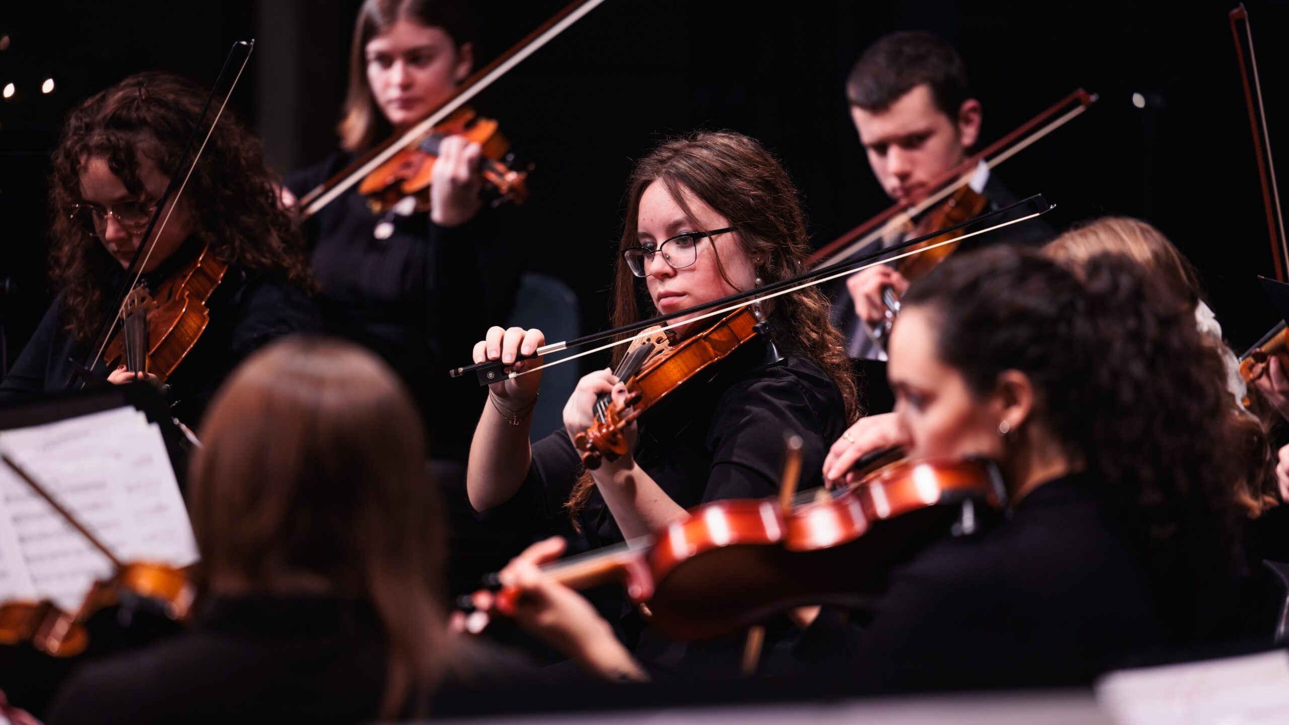 A group of young musicians playing violins together during a Christmas at Corban, showcasing their talent and teamwork.
