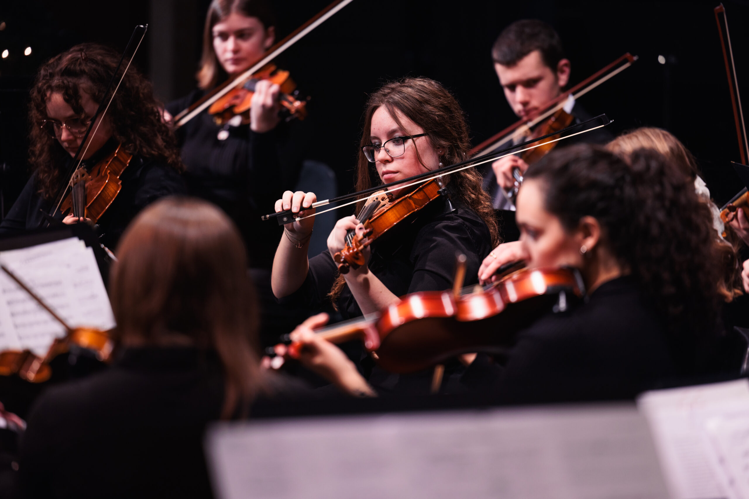 A group of young musicians playing violins together during a Christmas at Corban, showcasing their talent and teamwork.
