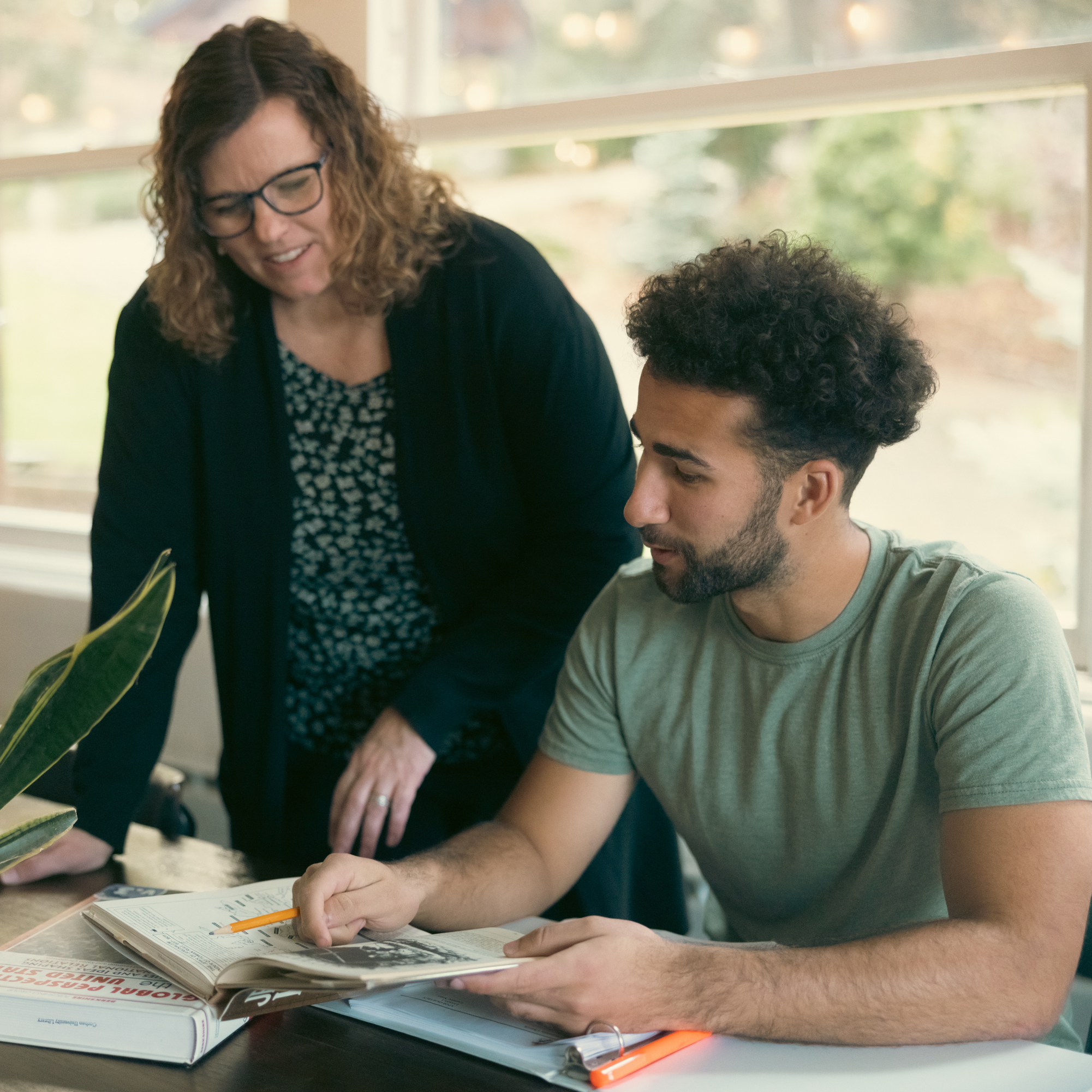 A woman tutors a student on a college assignment.
