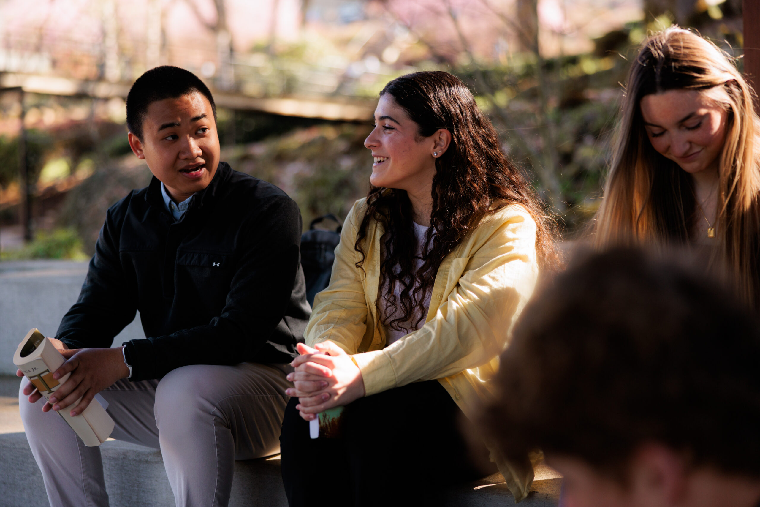 Students sitting together, engaged in conversation and enjoying the outdoors.