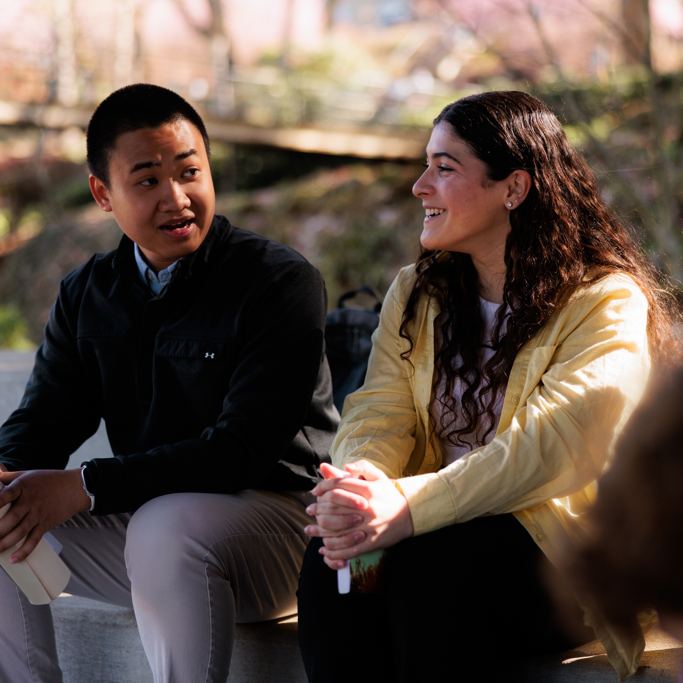 A man and a woman sitting together, engaged in conversation and enjoying the outdoors.