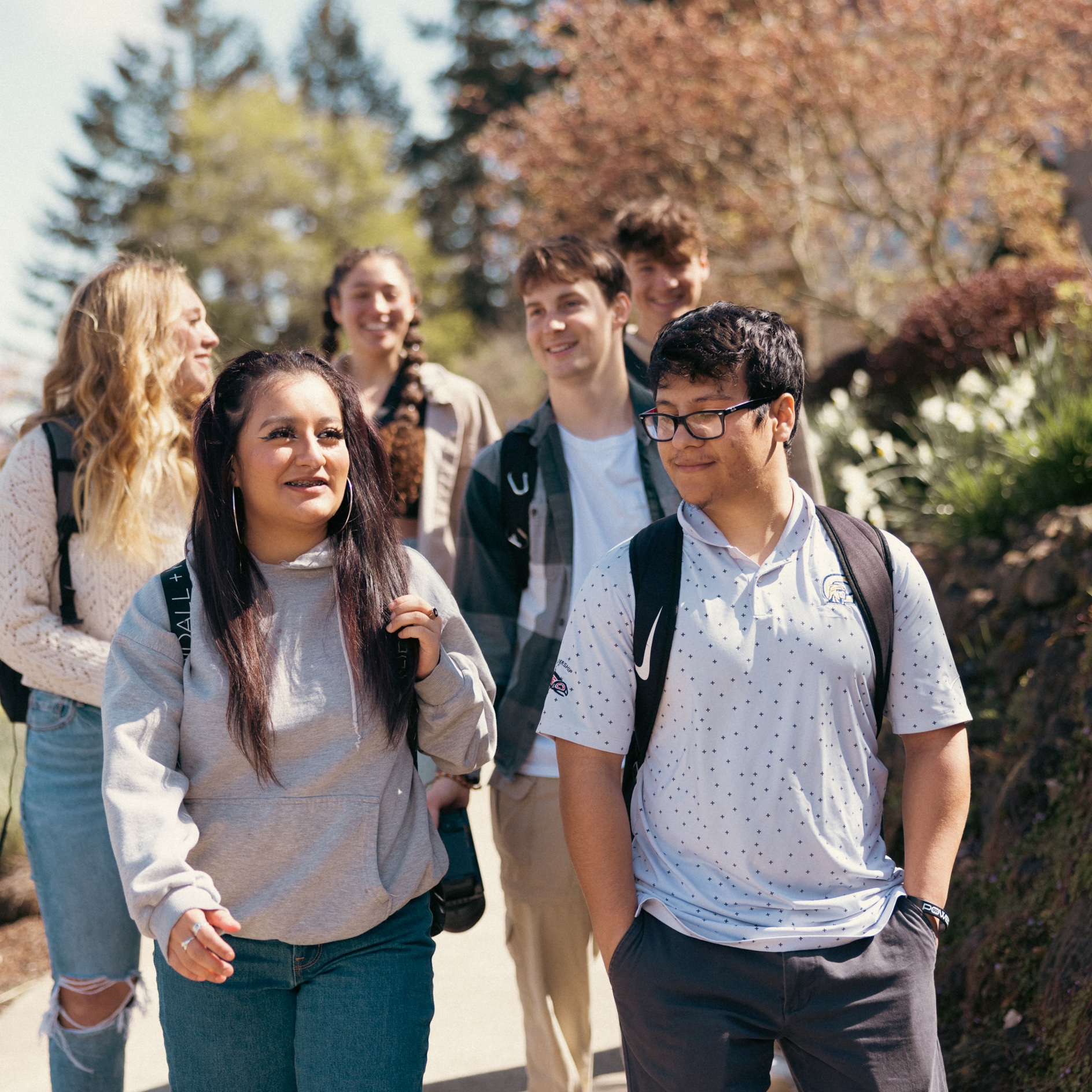A group of young people walking together along a scenic path surrounded by greenery.