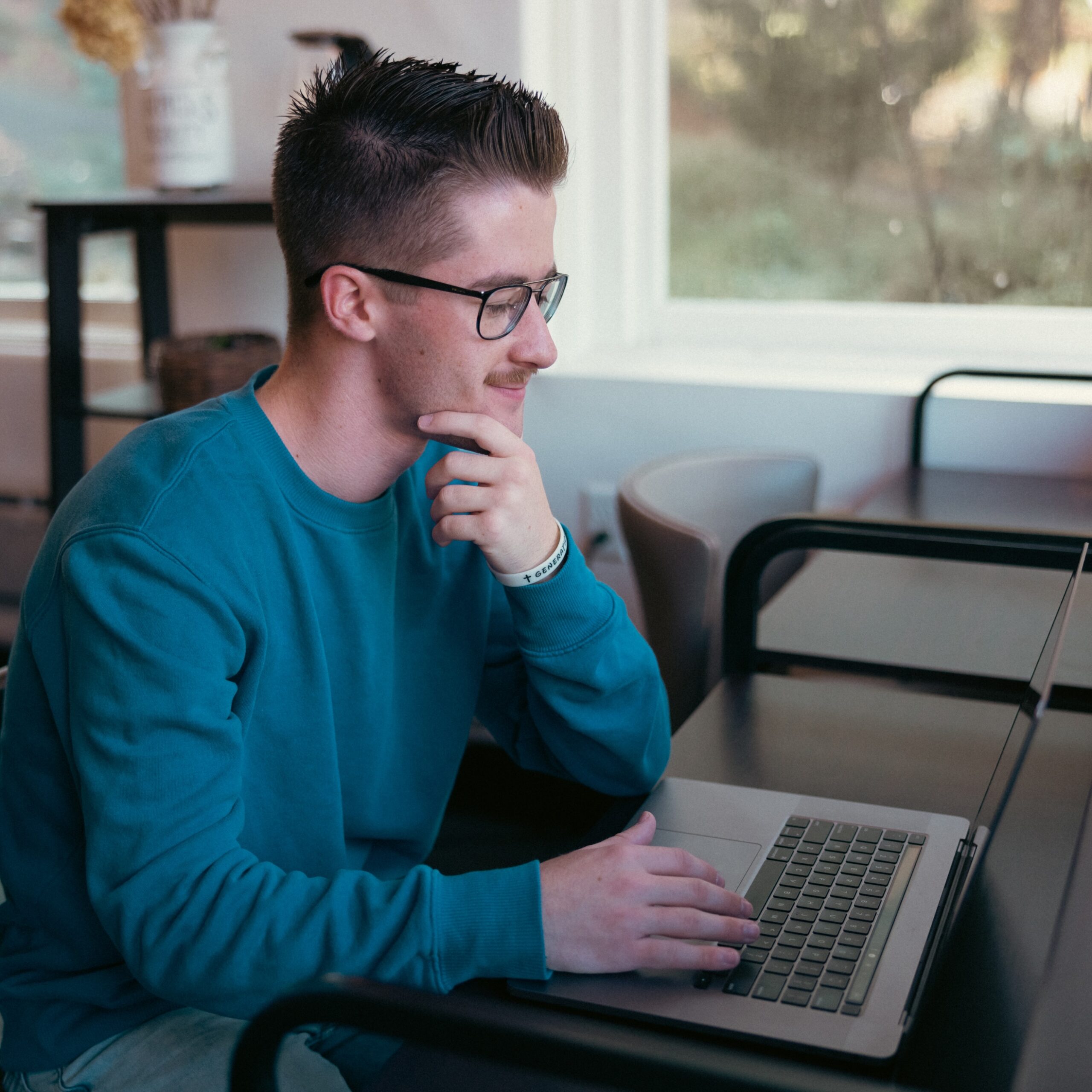 A man seated at a desk, focused on his work with a laptop.