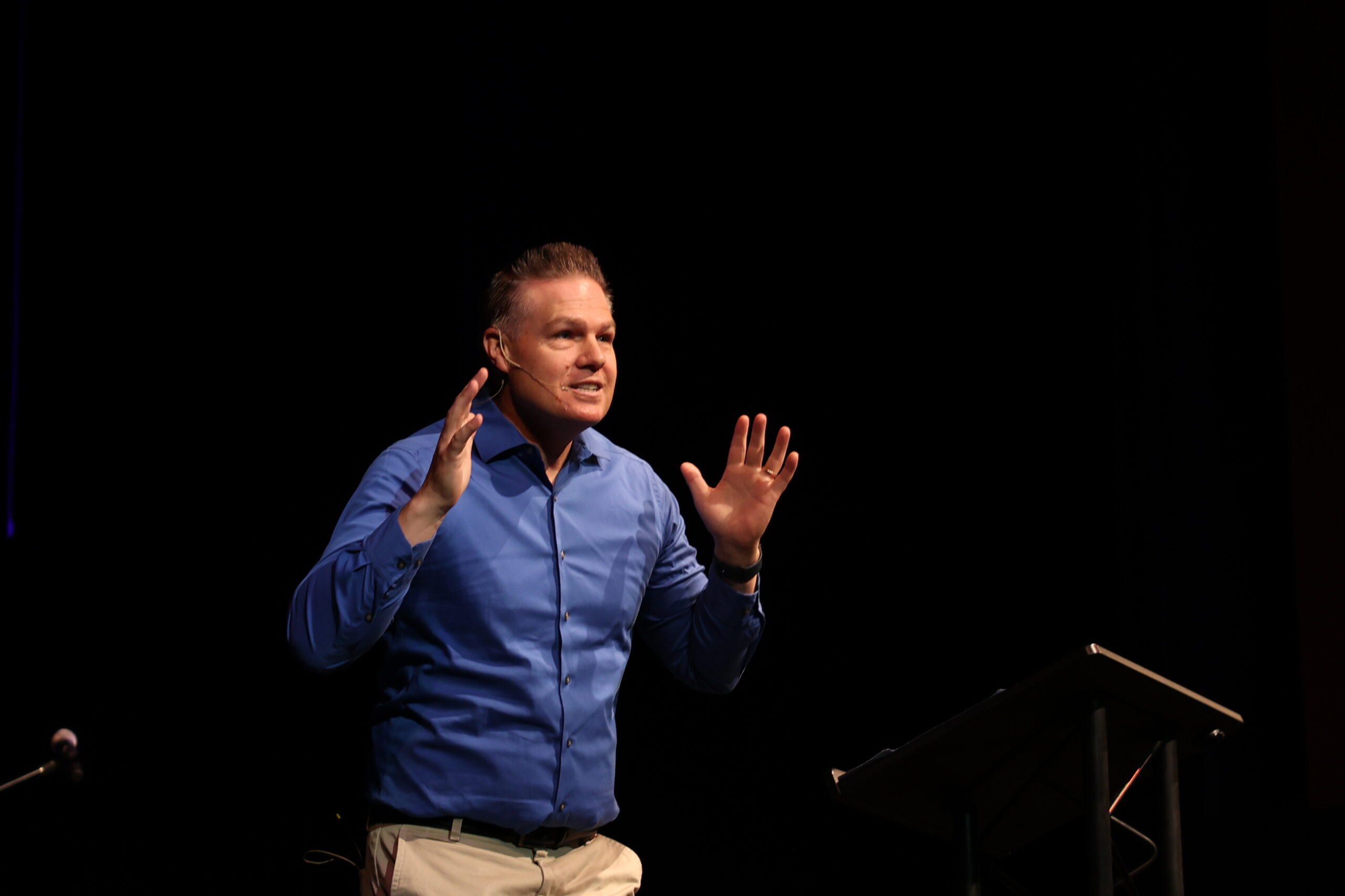 A man delivering a sermon at chapel, standing at a podium.