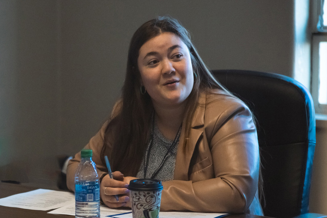 A woman sits at a desk, engaged in conversation.