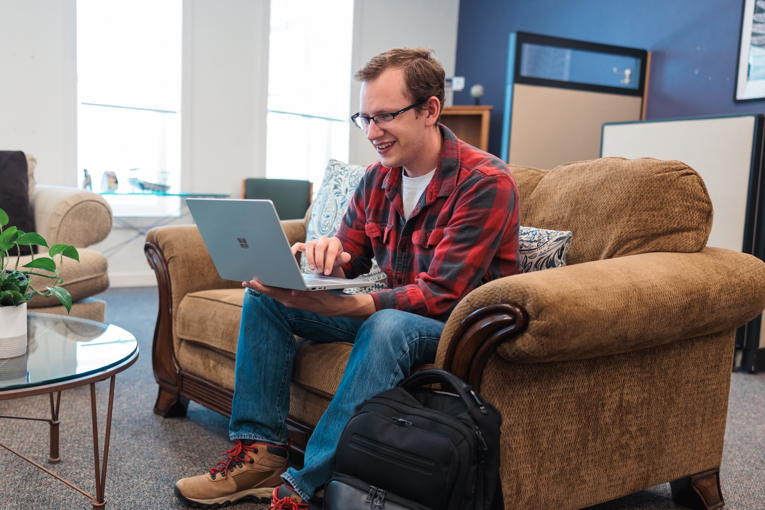 A man seated on a couch, studying in a cozy student study space.