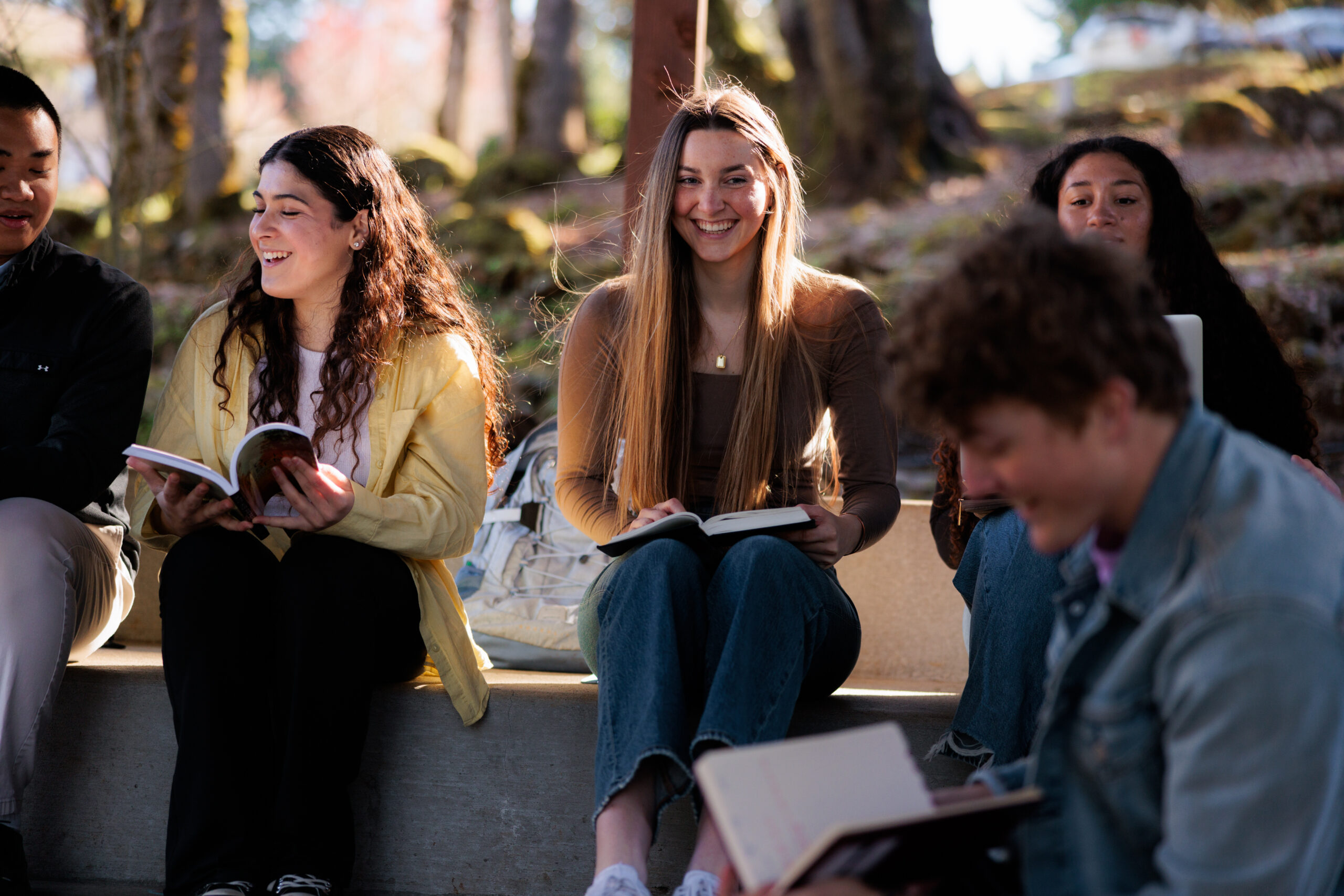A small group of college students sit together in an amphitheater talking and studying.