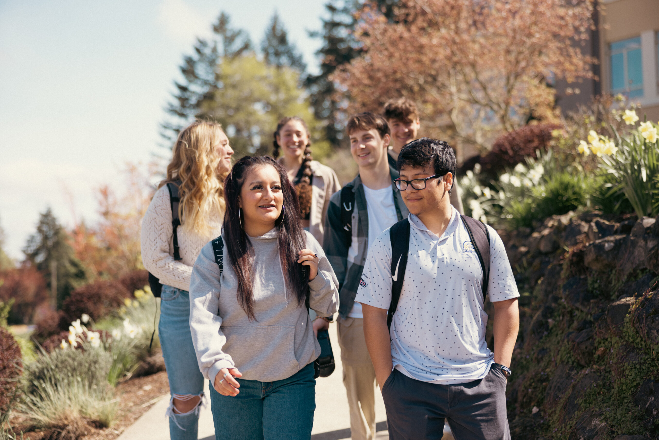 A group of young people walking together along a scenic path surrounded by greenery.