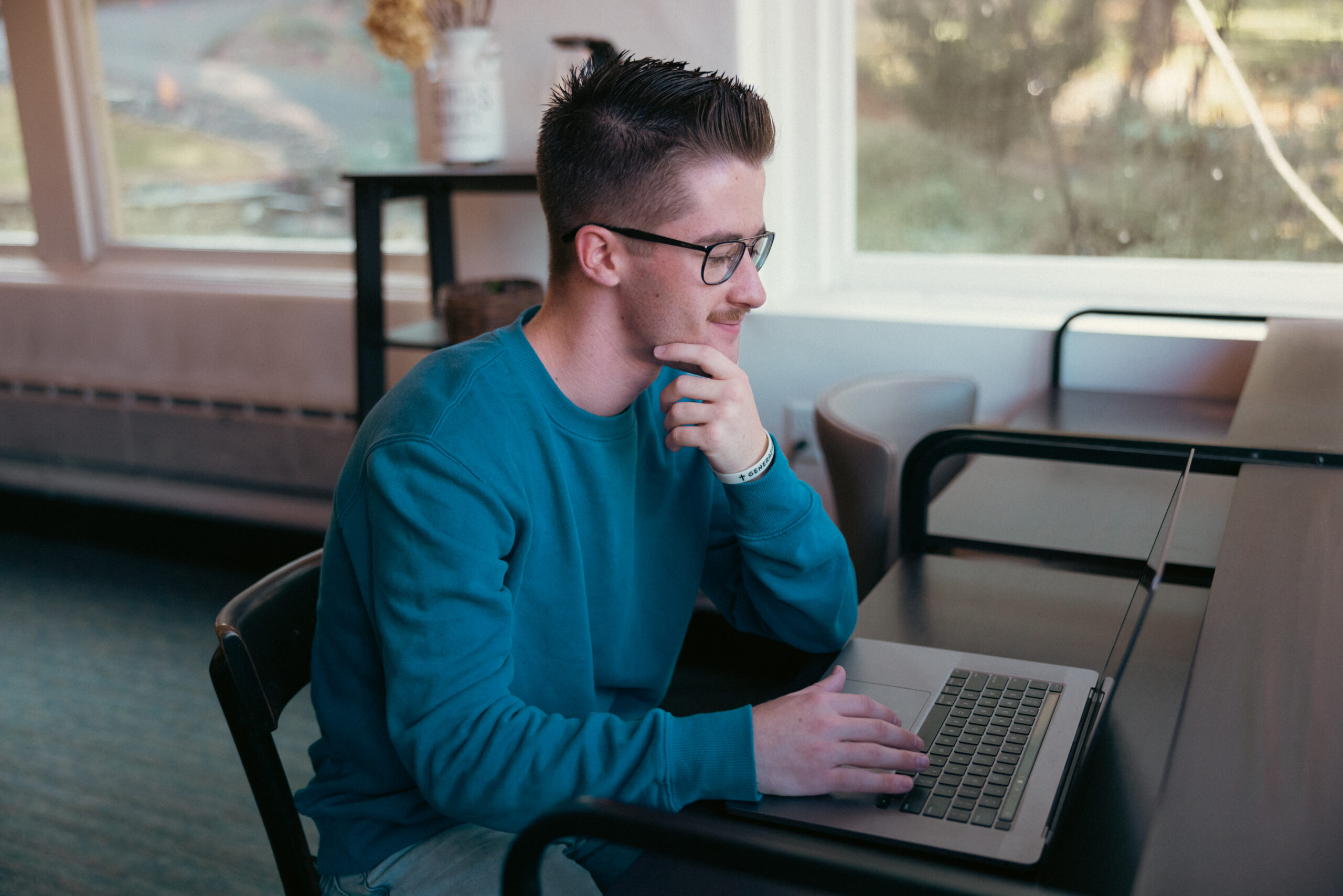 A man seated at a desk, focused on his work with a laptop.