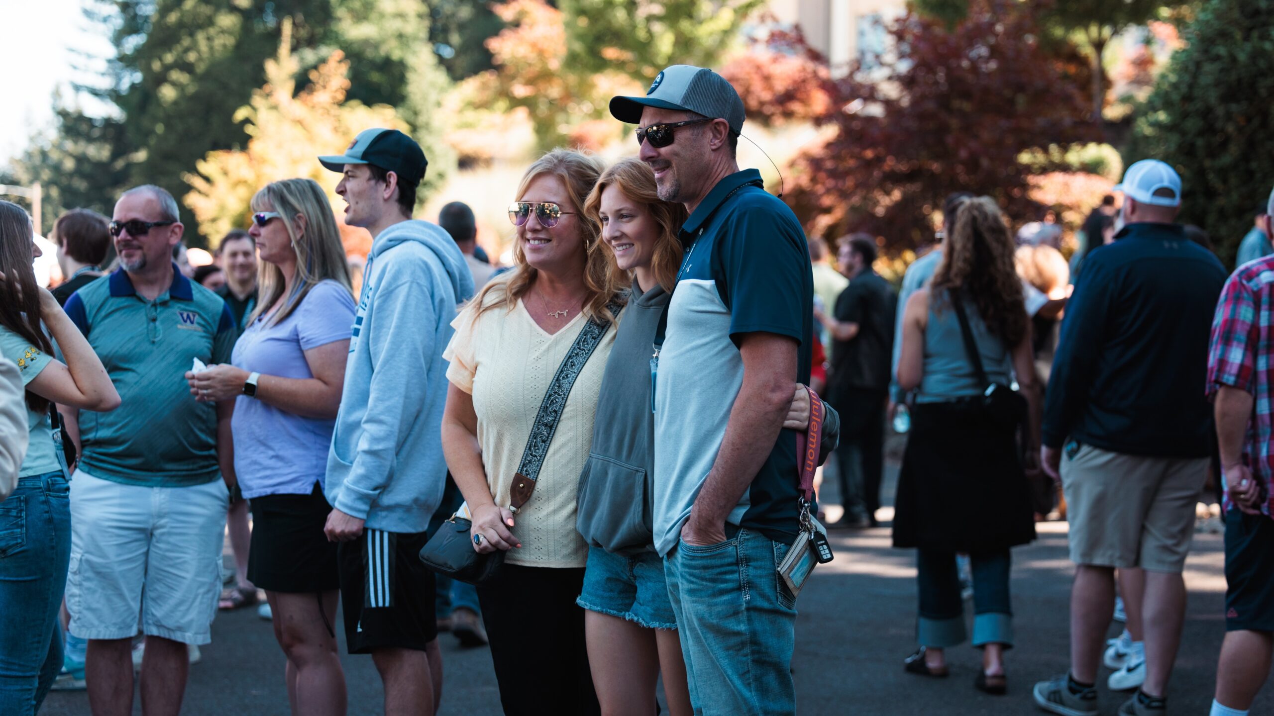 A group of people standing in a crowd, a lively atmosphere. A family in the center poses for a photo.