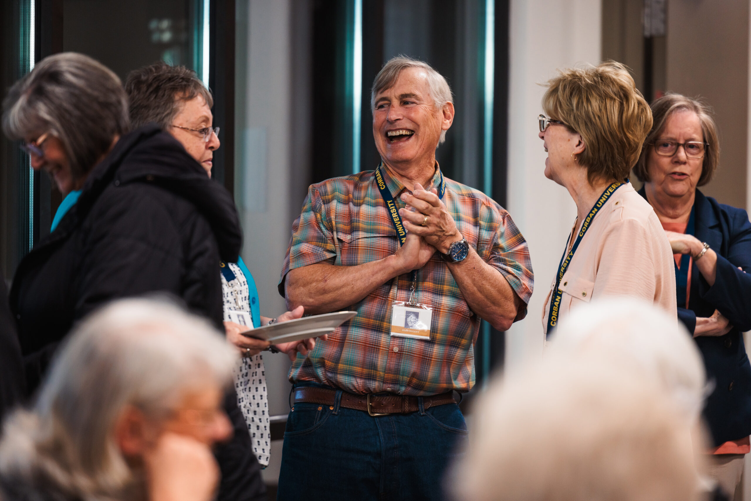 A group of golden grads engage in lively conversation, laughing together in a cheerful atmosphere.