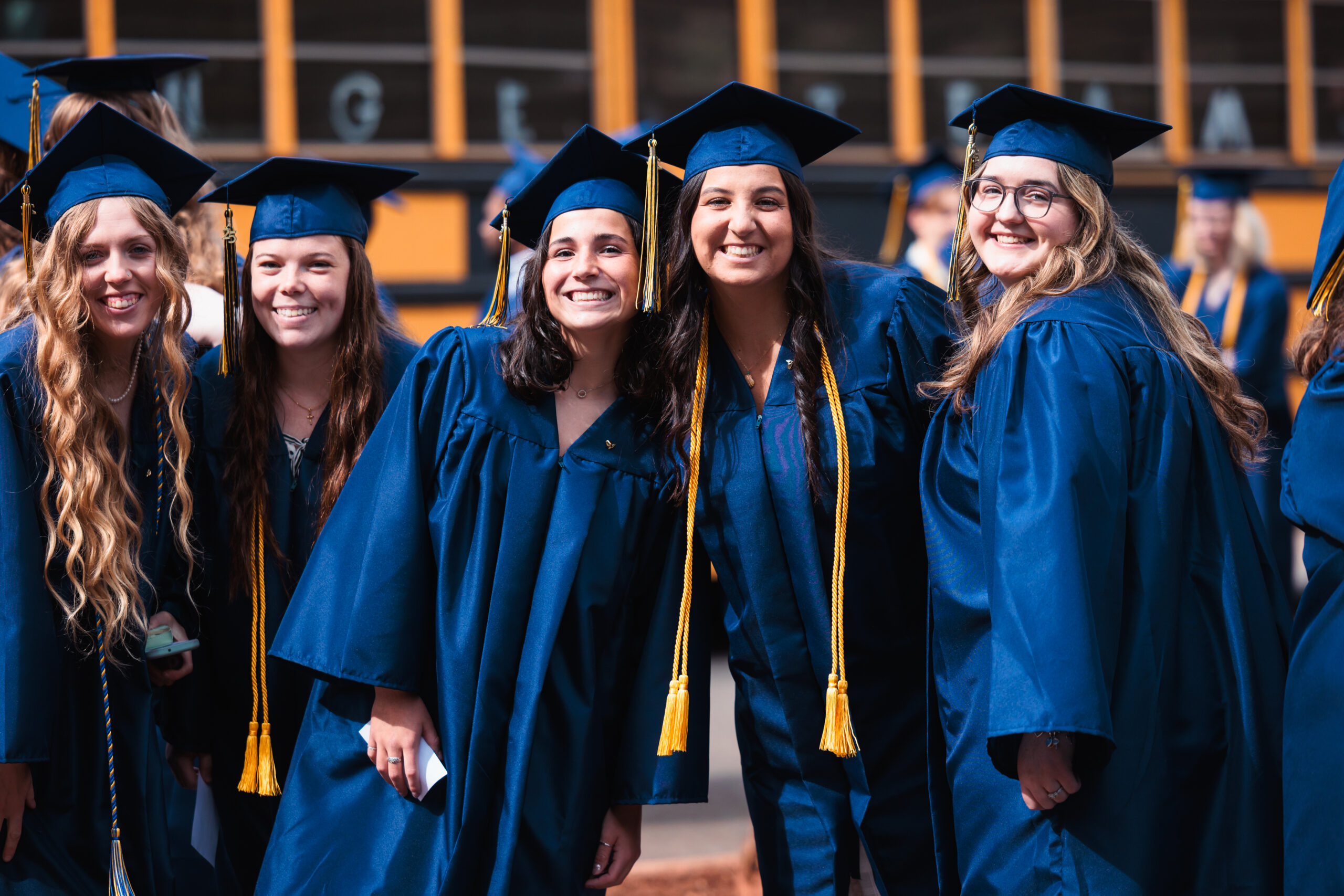 A group of graduates in caps and gowns pose for a photo outside before their commencement ceremony.
