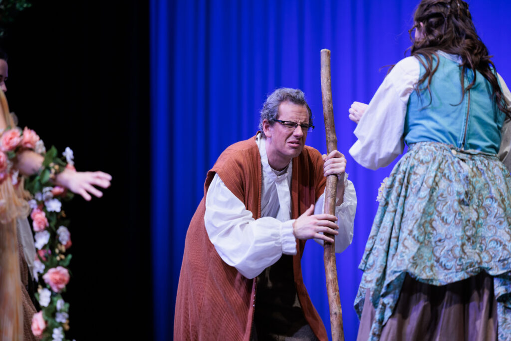 A man in costume holds a stick, with one women, during a scene from the "Sleeping Beauty, Briar Rose" play.