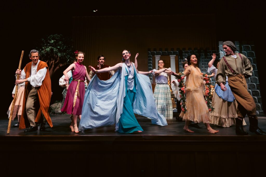 A group of actors in colorful costumes dancing on stage during the "Sleeping Beauty, Briar Rose" play.