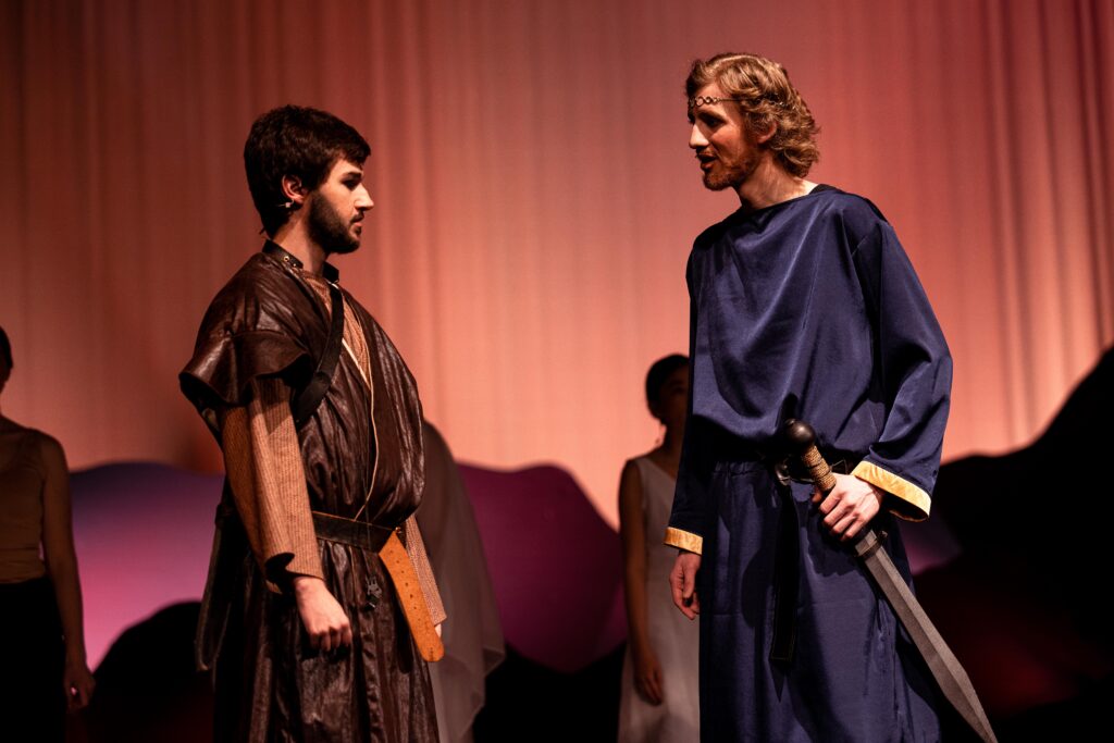 Two men dressed in costume converse in front of a mountain backdrop in "Tragedy of King Saul" play.
