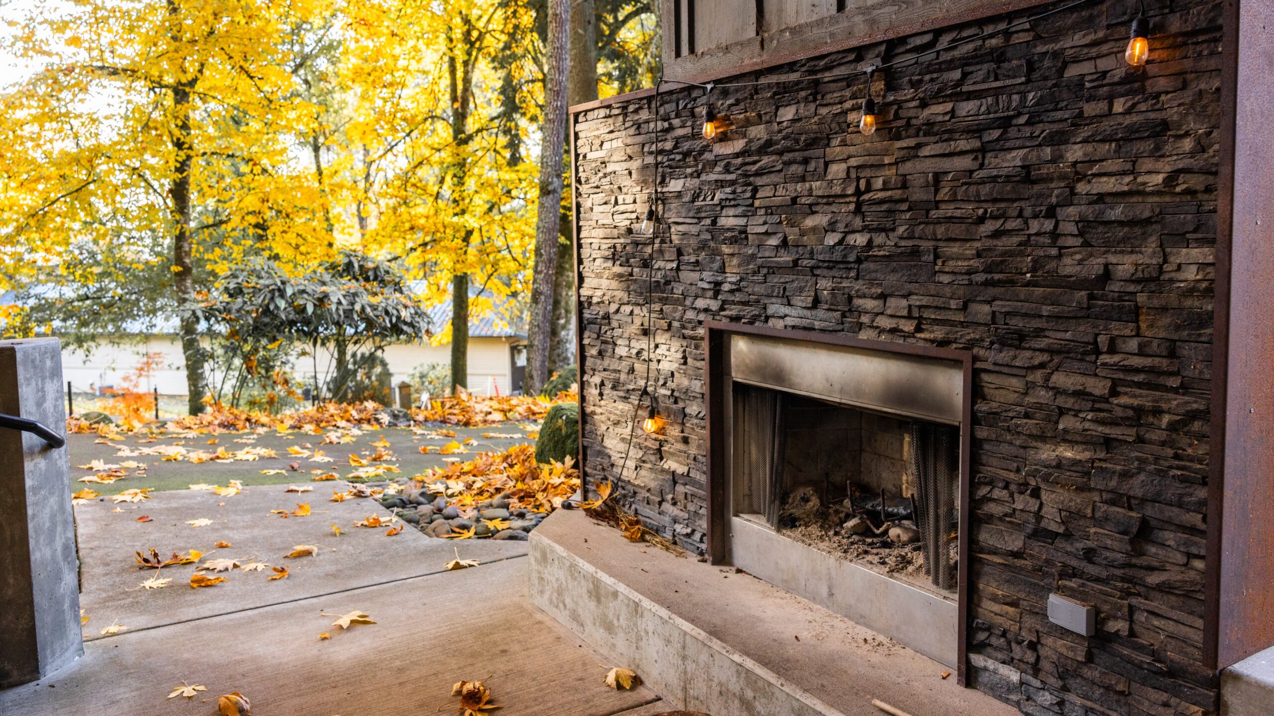 The stone fireplace in The Klatch serves as a central feature, adding charm to the outdoor community space.
