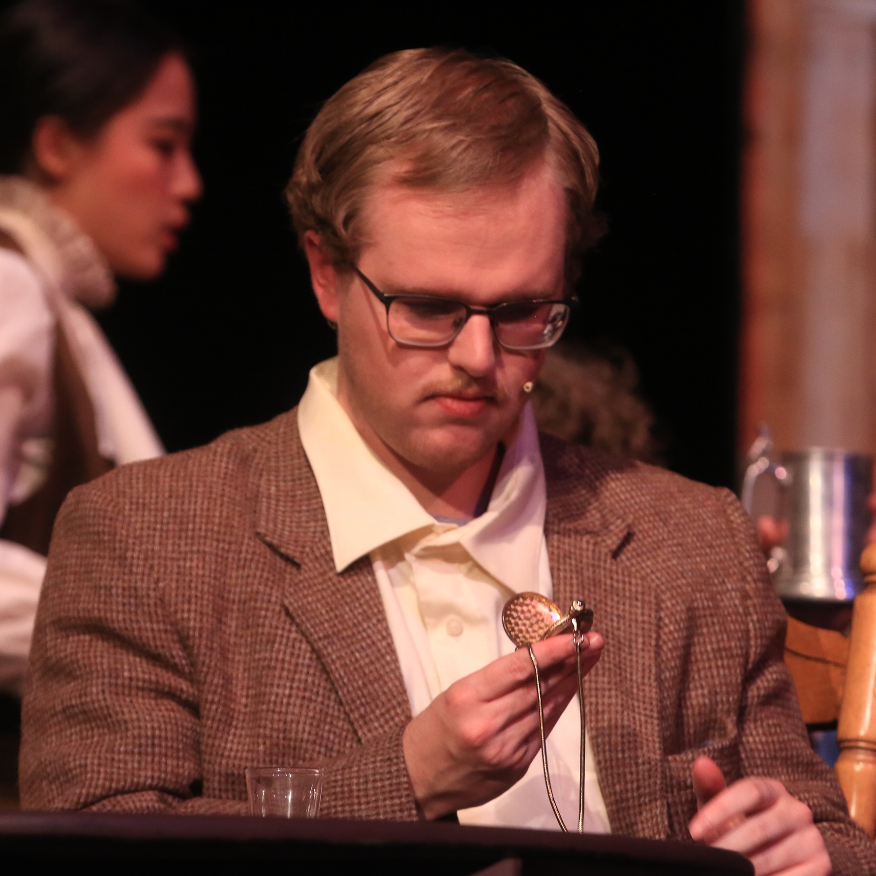 A man in glasses examines his pocket watch, in a scene from "Around the World in 80 Days" play.