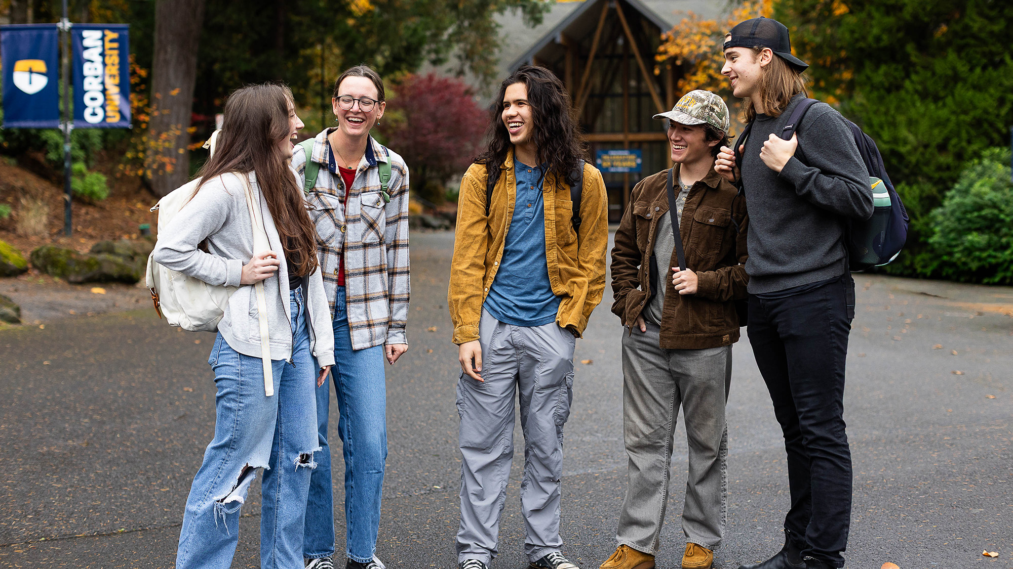 Five young people stand together smiling in front of a modern building.