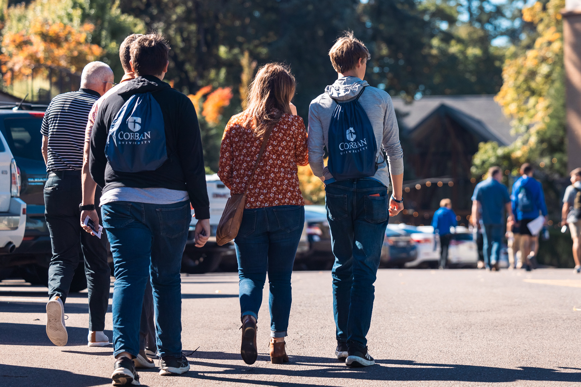 A group of people walking on a college campus tour at Corban.