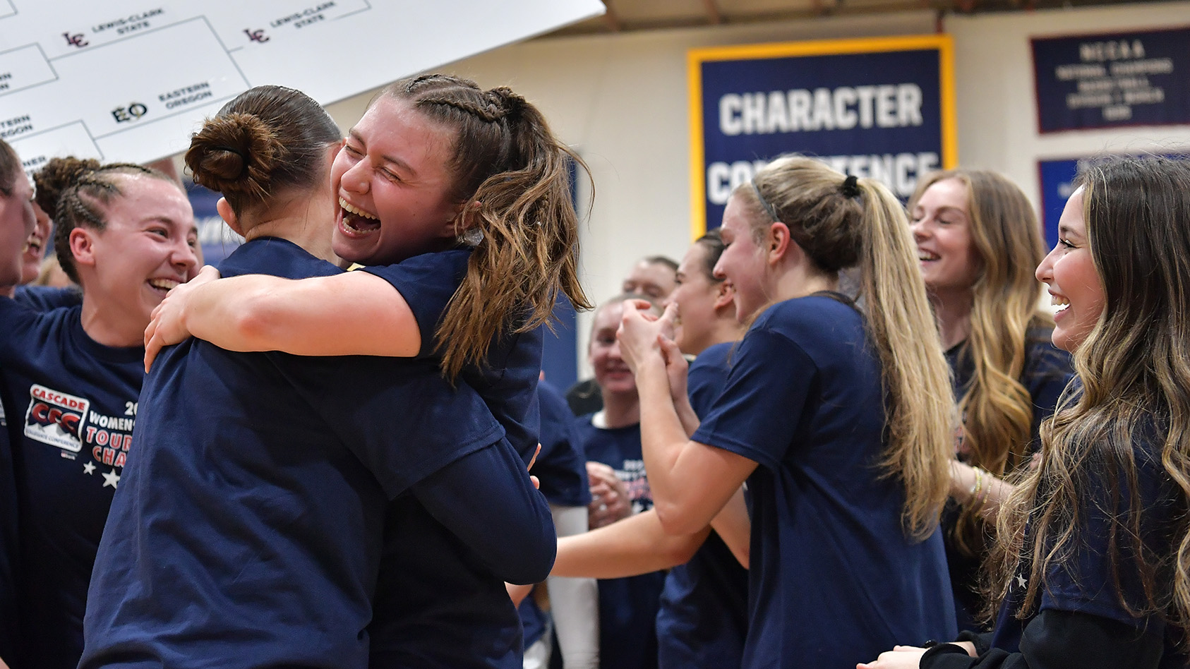 The women's basketball team joyfully celebrates their state championship victory, embracing and cheering together.