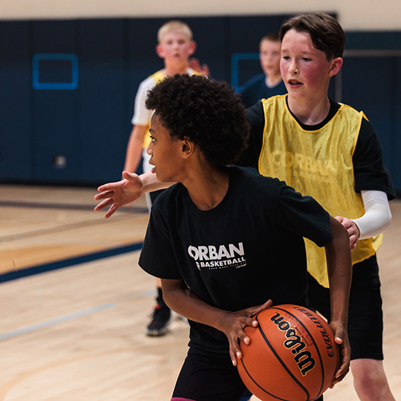 Two young boys compete in a basketball game during camp