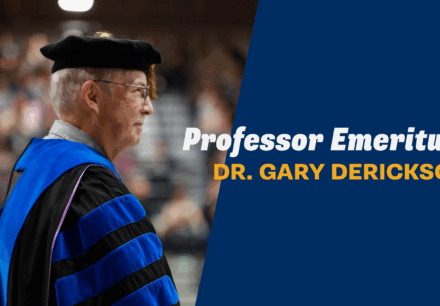 Dr. Gary Derickson in academic regalia at Corban University commencement, honored as Professor Emeritus