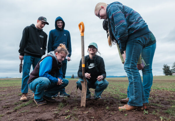 Corban University agriculture science students gather in a farm field to conduct soil sampling and evaluate field conditions during a hands-on learning experience with a local agricultural partner.