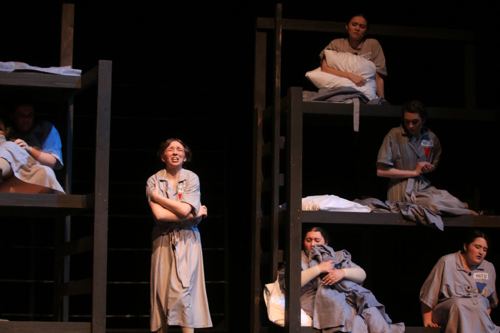 a group of women itch and hold themselves in pain in a barracks in a scene from The Hiding Place play